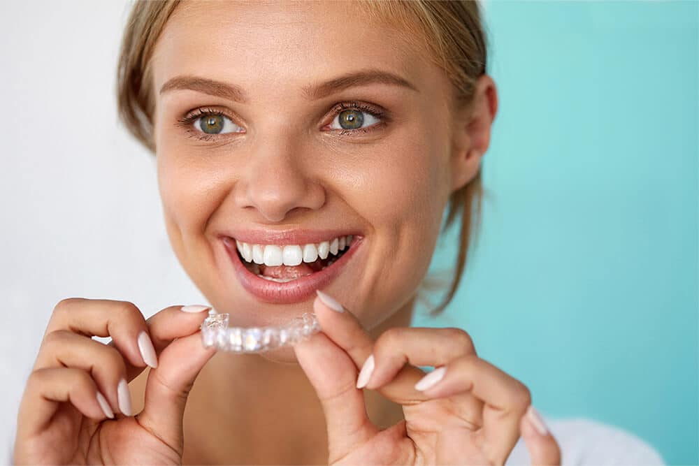 young woman is holding an invisalign aligners